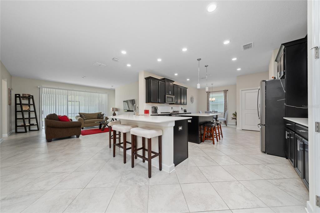 1701 Snapper Street St. Cloud, FL 34771 - Photo 7 of 29 a kitchen with stainless steel appliances kitchen island granite countertop a table chairs sink and cabinets