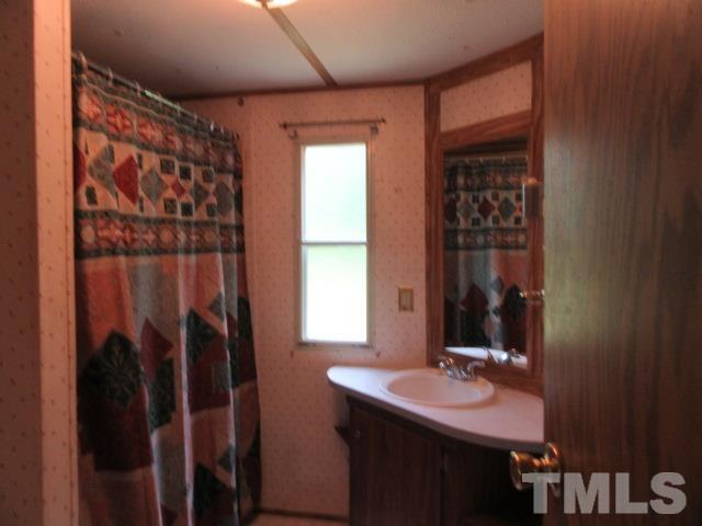 9565 George Ruff Road Bullock, NC 27507 - Photo 10 of 15 a bathroom with a sink a mirror and a shower