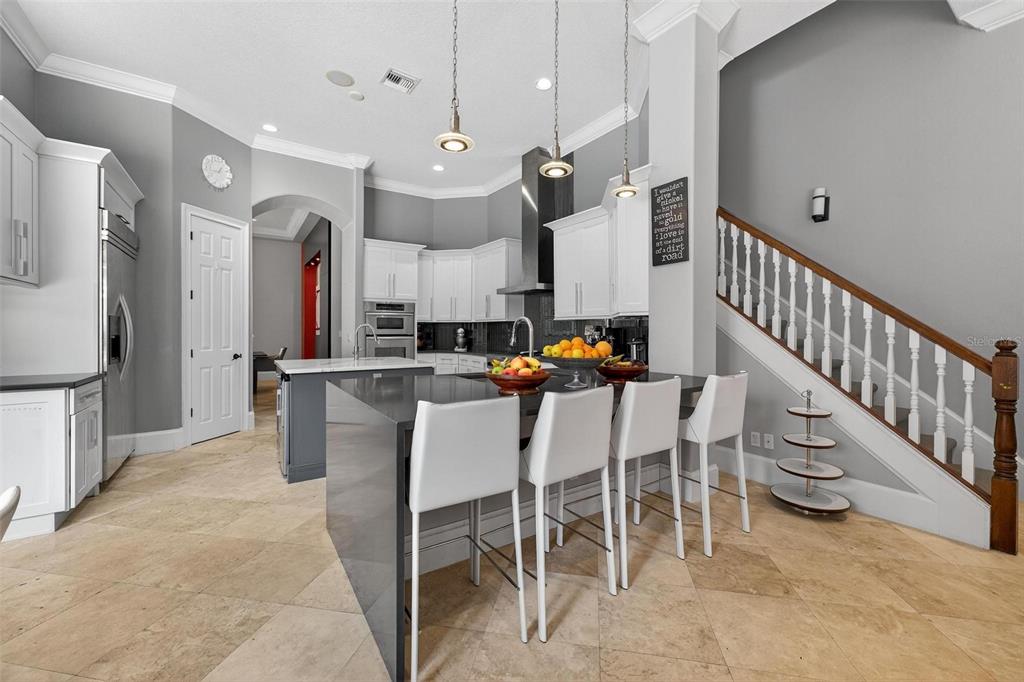 11015 Hawkshead Court Windermere, FL 34786 - Photo 48 of 90 a dining room with stainless steel appliances kitchen island granite countertop a table chairs and a refrigerator