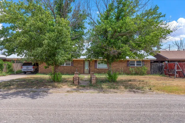 a view of a house with a yard and large tree