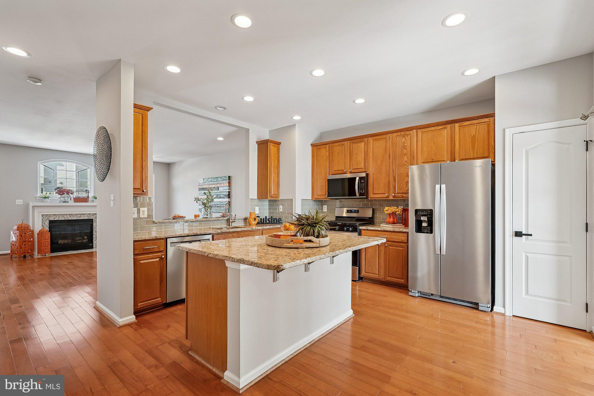 22982 Fox Fire Terrace Brambleton, VA 20148 - Photo 22 of 50 a kitchen with stainless steel appliances granite countertop a refrigerator a stove top oven a sink dishwasher and white cabinets with wooden floor