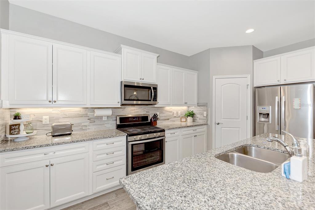 11616 Golden Bay Place Lakewood Ranch, FL 34211 - Photo 22 of 66 a kitchen with granite countertop a sink stainless steel appliances and white cabinets