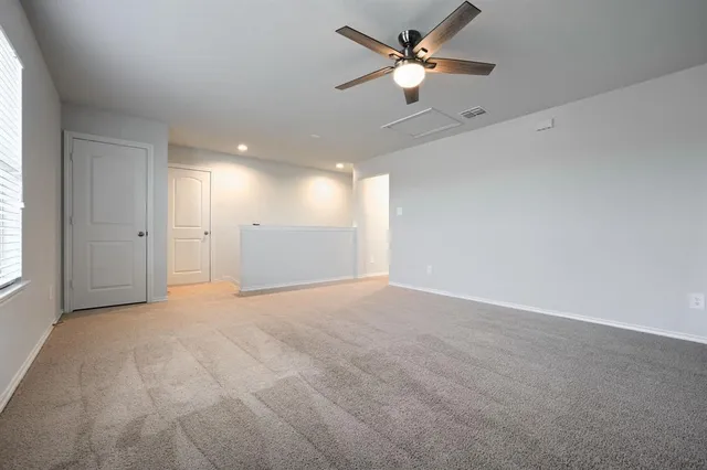 an empty room with chandelier fan and windows