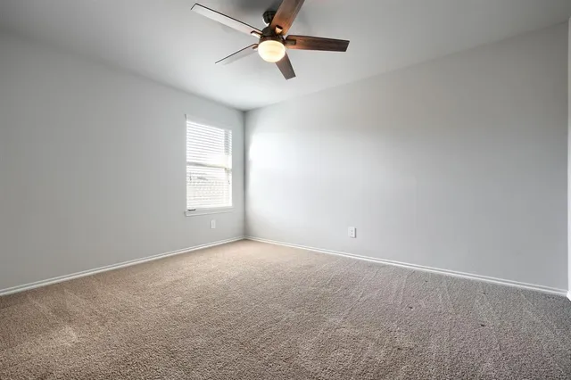 an empty room with windows and fan chandelier fan