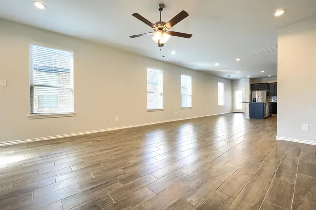 a view of an empty room with window and wooden floor