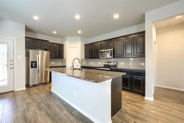 a large kitchen with stainless steel appliances granite countertop a stove a sink and a refrigerator