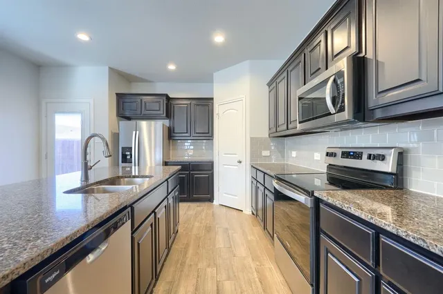 a kitchen with stainless steel appliances granite countertop a sink stove microwave and cabinets