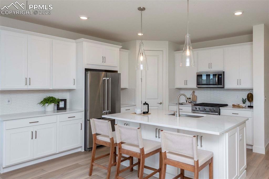 2036 Peachleaf Loop Castle Rock, CO 80108 - Photo 11 of 35 a kitchen with stainless steel appliances a stove a sink refrigerator and white cabinets with wooden floor
