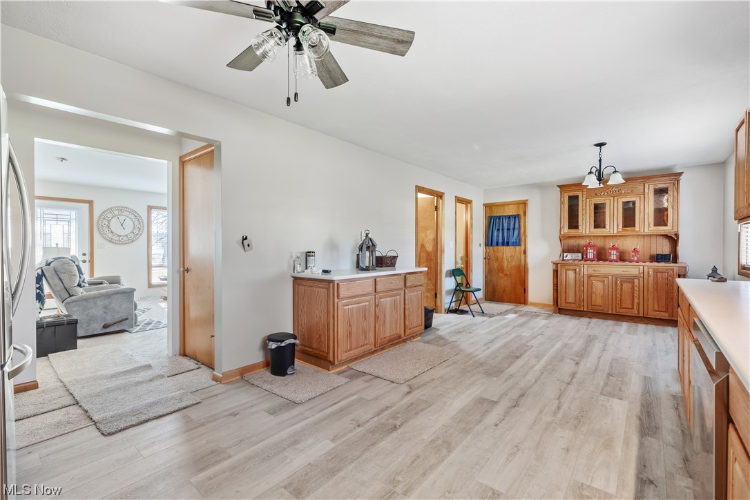 22814 Buck Road Alliance, OH 44601 - Photo 4 of 17 Kitchen with pendant lighting, light hardwood / wood-style floors, and ceiling fan with notable chandelier