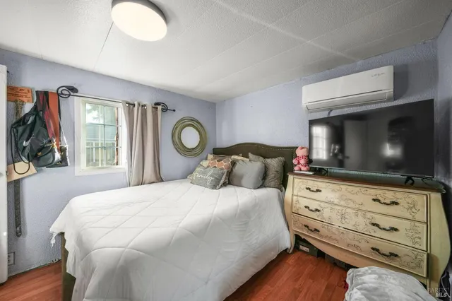 a bedroom with a bed and a flat tv screen on dresser