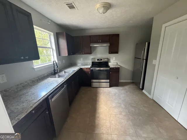 a kitchen with stainless steel appliances granite countertop a sink stove and refrigerator