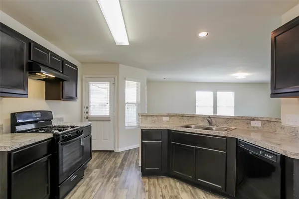 a kitchen with granite countertop stainless steel appliances a sink stove top oven and cabinets