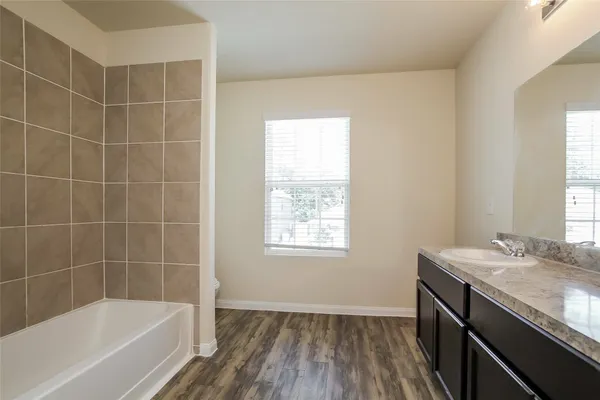 a bathroom with a granite countertop sink a bathtub window and shower