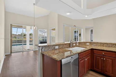 a hall with granite countertop a sink and dishwasher with wooden floor