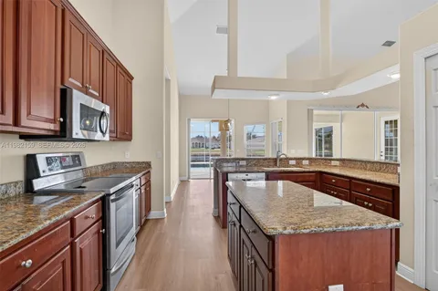 a kitchen with granite countertop stainless steel appliances a sink a counter top space and cabinets