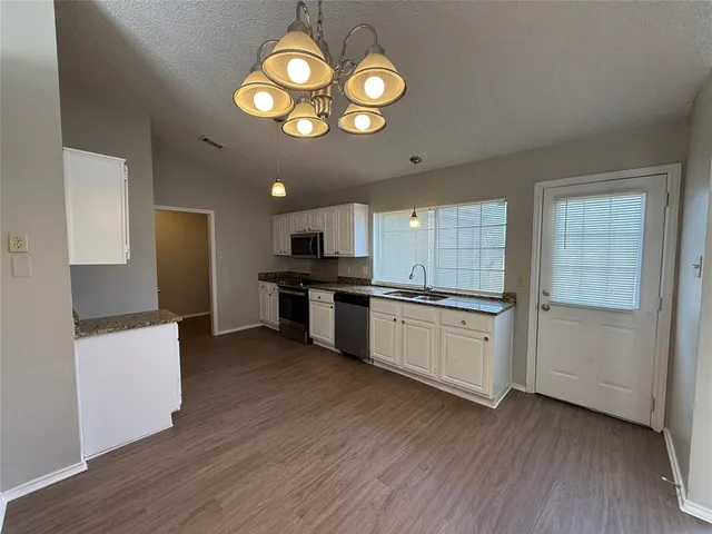 a large kitchen with stainless steel appliances granite countertop a stove and a wooden floors