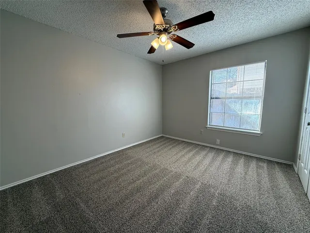 an empty room with a window and a fan