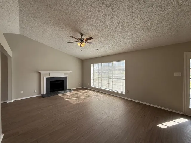 an empty room with windows fireplace and wooden floor