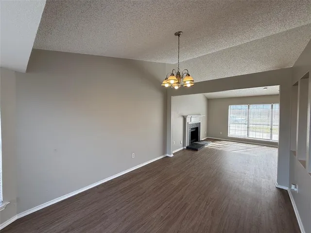an empty room with wooden floor chandelier and windows
