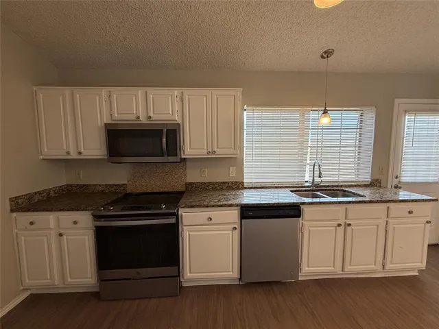 a kitchen with granite countertop white cabinets and appliances