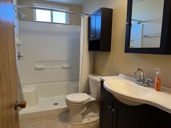 a bathroom with a sink a toilet and shower