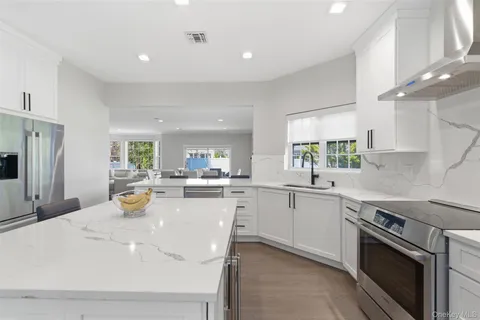 a kitchen with a sink a stove a refrigerator and white cabinets with wooden floor