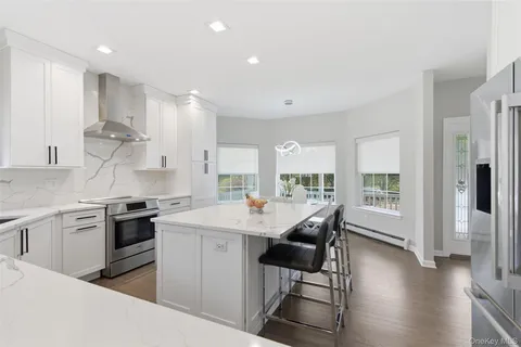 a kitchen with stainless steel appliances granite countertop a stove a sink dishwasher and a refrigerator with wooden floor