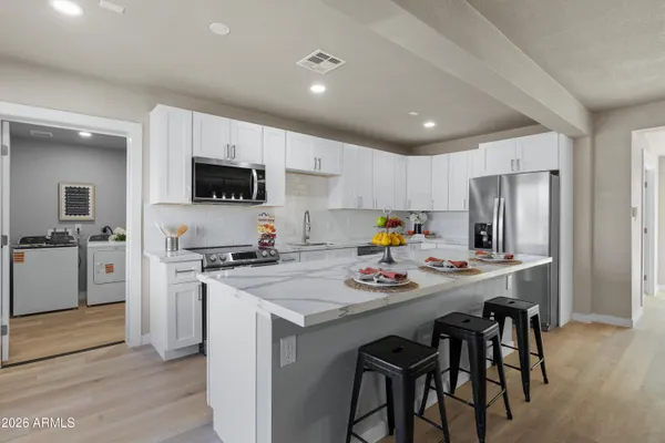 a kitchen with a sink a stove a refrigerator and white cabinets with wooden floor