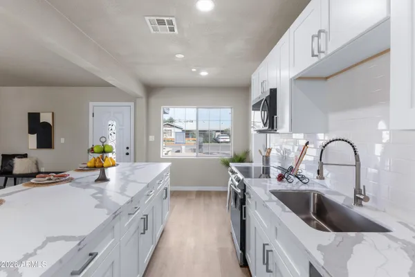 a kitchen with stainless steel appliances a sink a stove top oven a counter space and cabinets