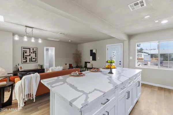 a kitchen with stainless steel appliances granite countertop a stove a sink a dining table and chairs with wooden floor