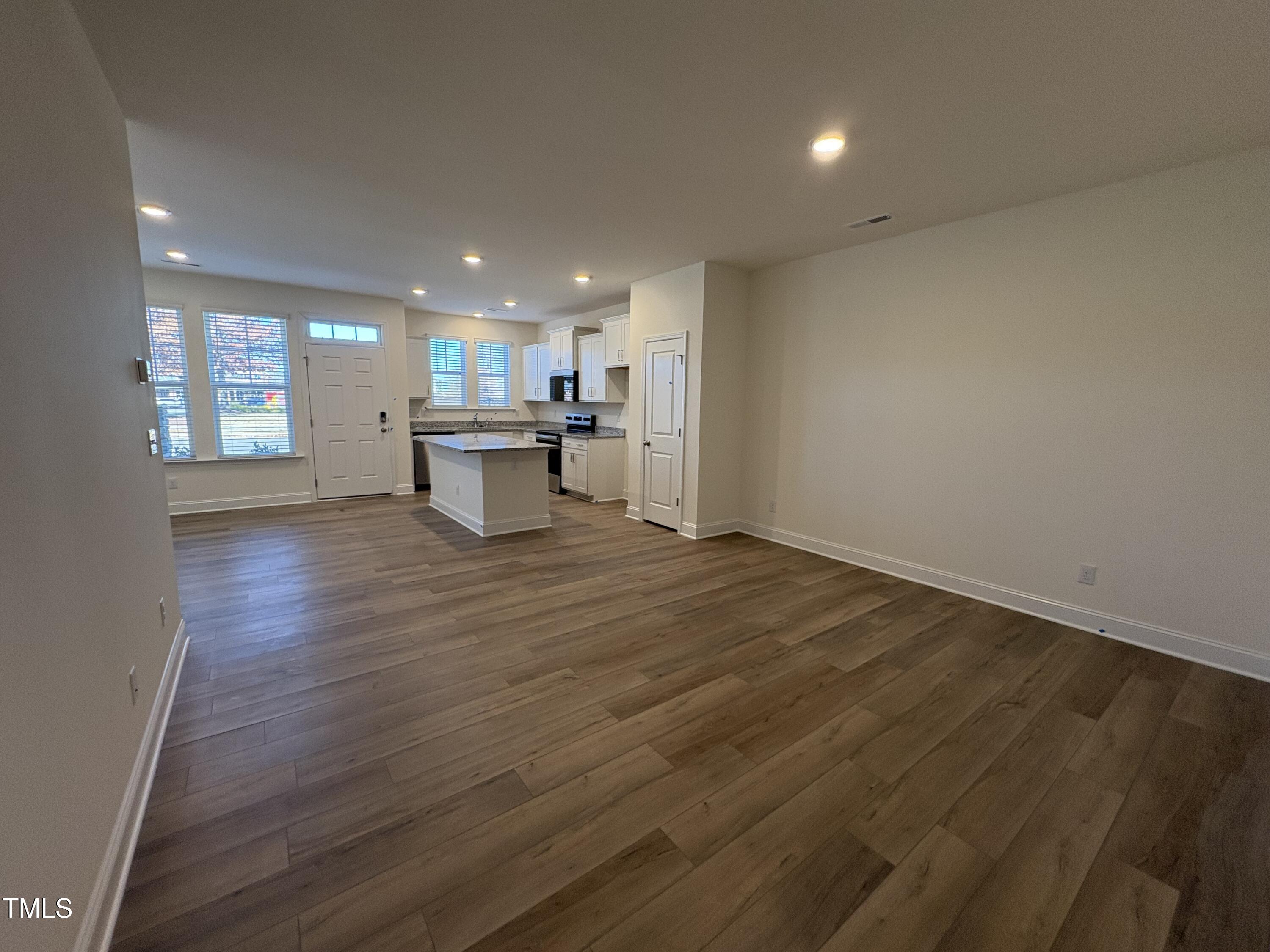 6316 Granite Quarry Drive Raleigh, NC 27610 - Photo 4 of 16 an empty room with wooden floor and a kitchen