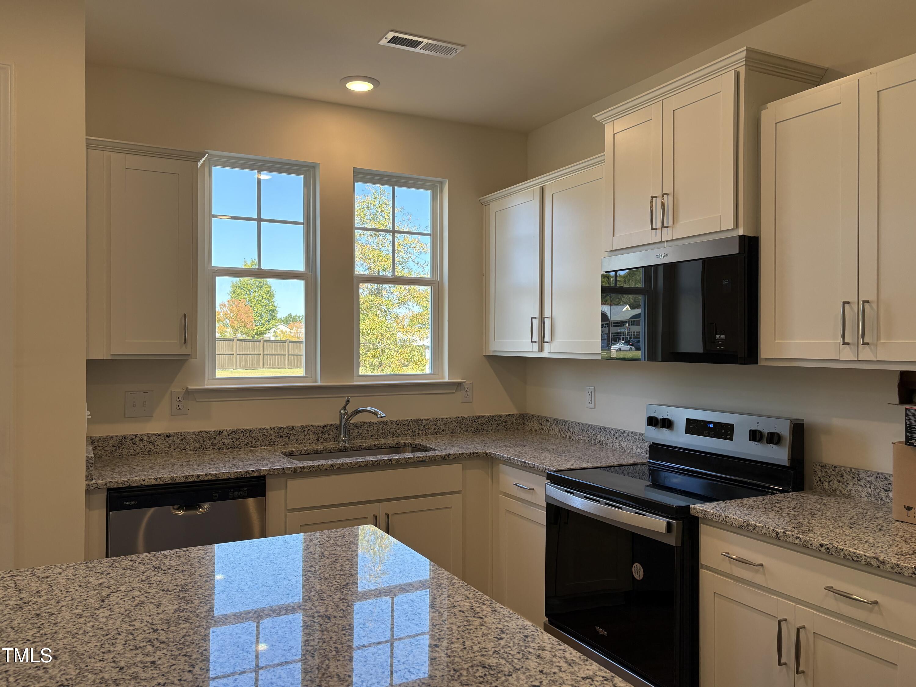 6316 Granite Quarry Drive Raleigh, NC 27610 - Photo 6 of 16 a kitchen with granite countertop white cabinets sink and stainless steel appliances