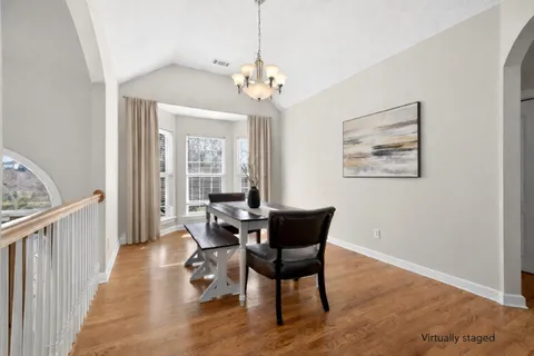 a dining room with wooden floor a chandelier a wooden table and chairs
