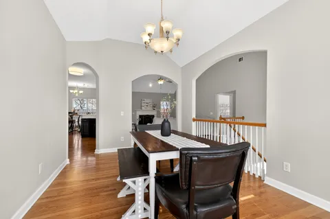 a dining room with wooden floor a chandelier a wooden table and chairs