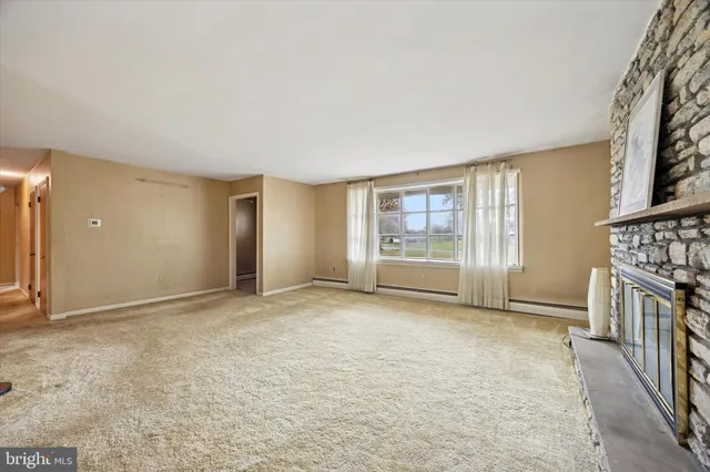 a view of an empty room with a fireplace and a window