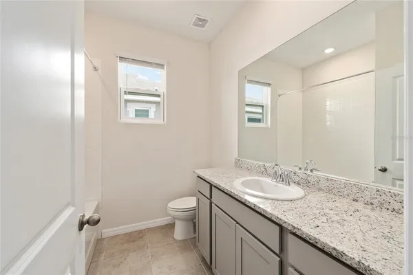 a view of an empty room with closet and a bathroom