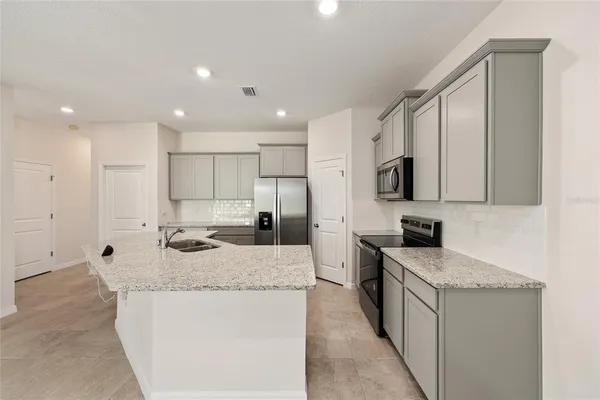 a kitchen with granite countertop kitchen island stainless steel appliances a refrigerator stove microwave and sink