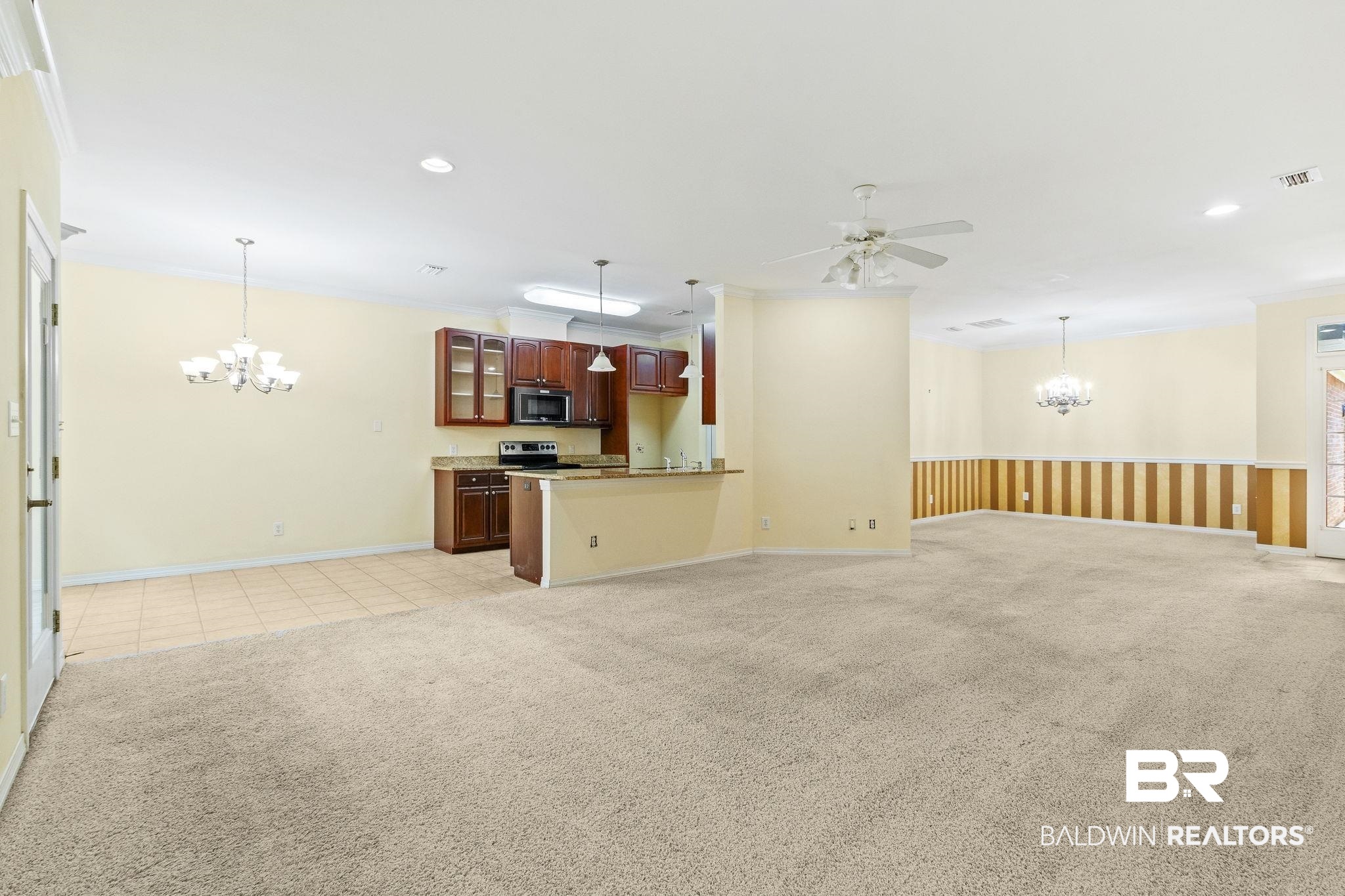 166 Club Drive Fairhope, AL 36532 - Photo 8 of 41 Unfurnished living room featuring ceiling fan with notable chandelier, crown molding, and light colored carpet