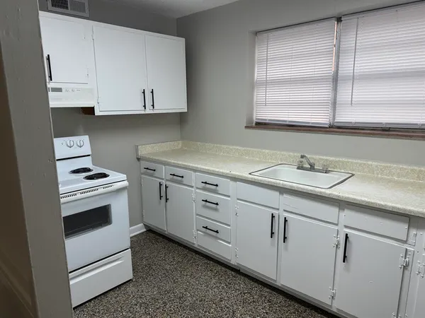 a kitchen with cabinets appliances a sink and a window