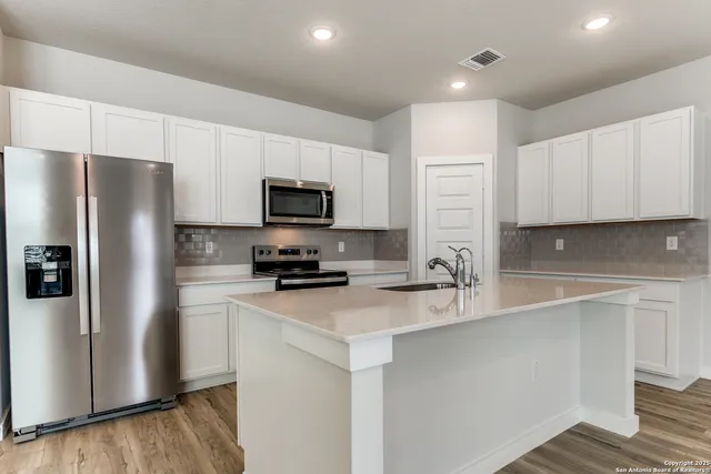 a kitchen with a refrigerator a microwave a sink and cabinets