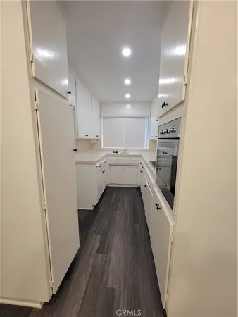 a kitchen with a refrigerator a sink and wooden floor