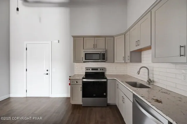 a kitchen with granite countertop a sink stove and refrigerator