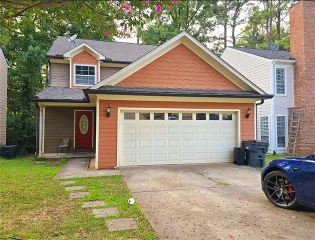 a front view of a house with a garden and parking space