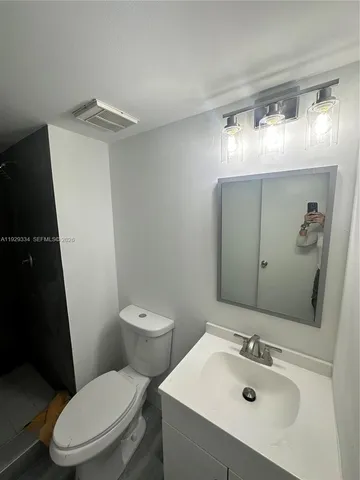 a white toilet sitting next to a bathroom sink and a mirror