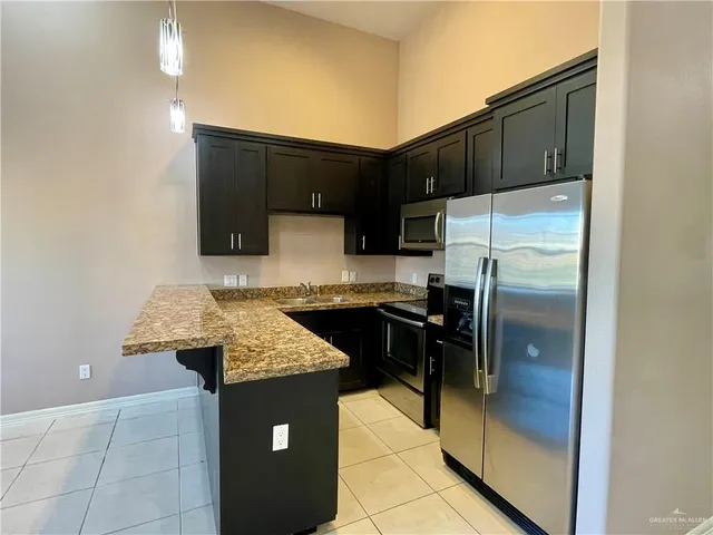 a kitchen with kitchen island granite countertop a refrigerator a stove and a sink with granite countertops