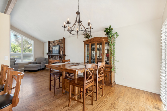 9832 Falconhurst Drive Sandy, UT 84092 - Photo 7 of 29 Open-concept living space featuring wood-finish flooring, a stone-accented fireplace, and a vaulted ceiling with exposed beams
