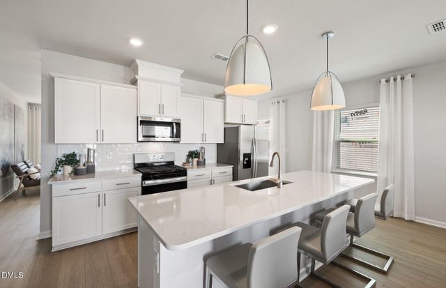 a kitchen with stainless steel appliances a sink a refrigerator and cabinets