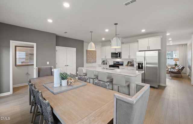 a kitchen with stainless steel appliances a sink a stove a refrigerator and white cabinets