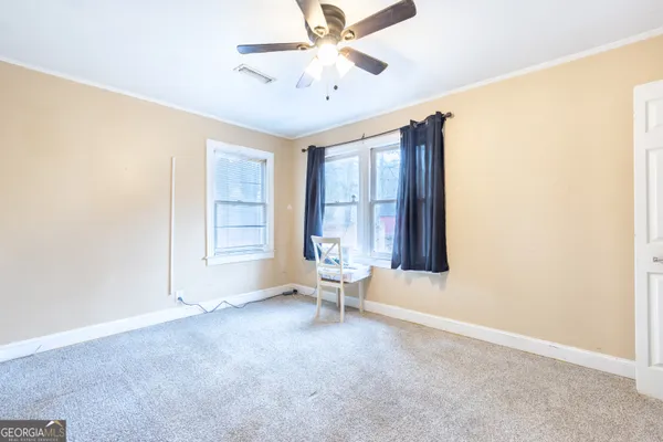 an empty room with windows and ceiling fan