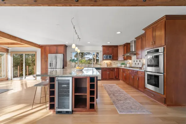 a kitchen with stainless steel appliances kitchen island granite countertop a table chairs sink and cabinets